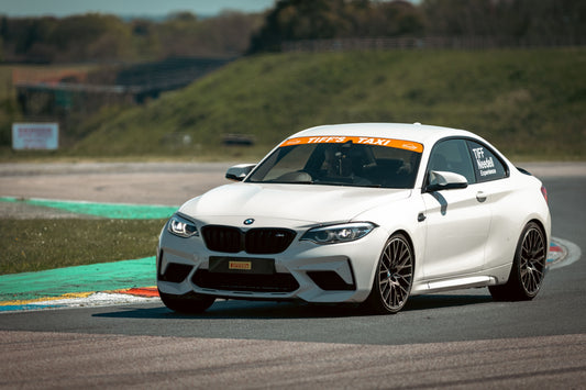 White BMW M2 Competition (F87) track-taxi car cornering hard on an English circuit