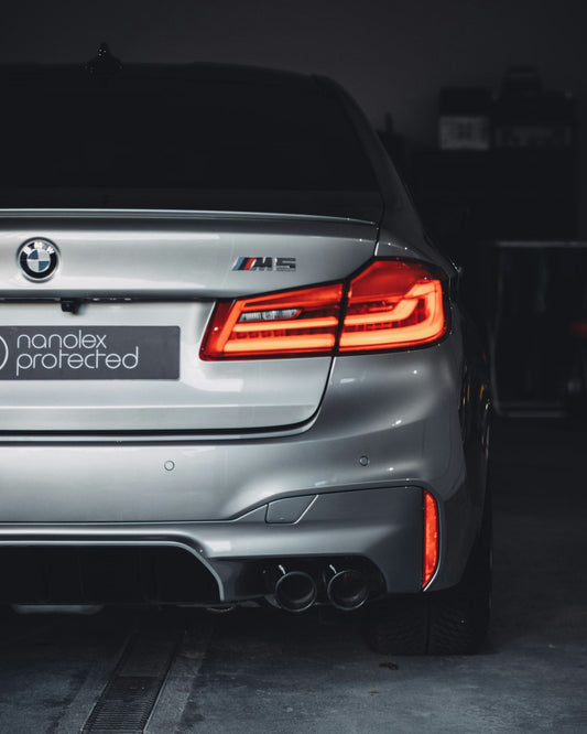 Grey BMW F90 M5 sedan parked on a city street, front three-quarter view