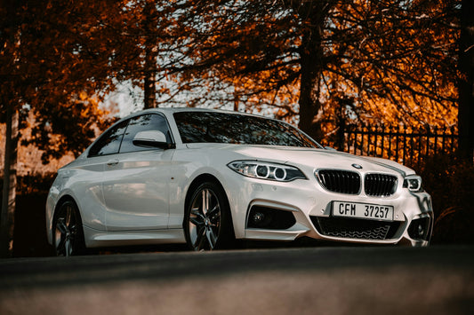 Blue BMW F87 M2 coupe driving on a mountain road, front three-quarter view