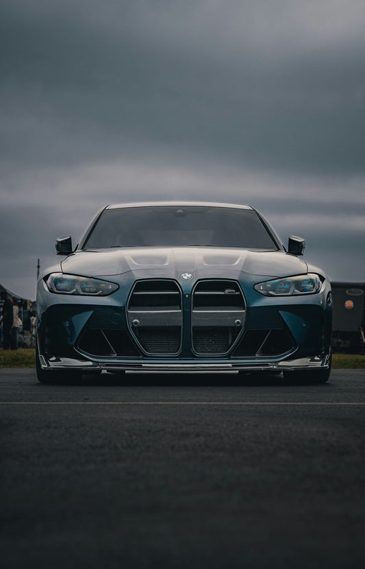 Front three-quarter view of a blue BMW G80 M3 with kidney grille and headlights