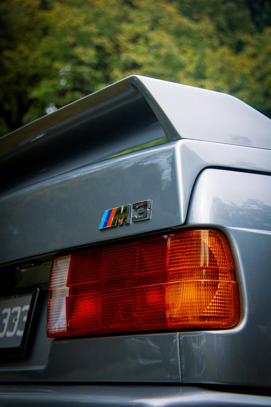 Rear three-quarter view of a classic BMW M3 parked at a community car meet